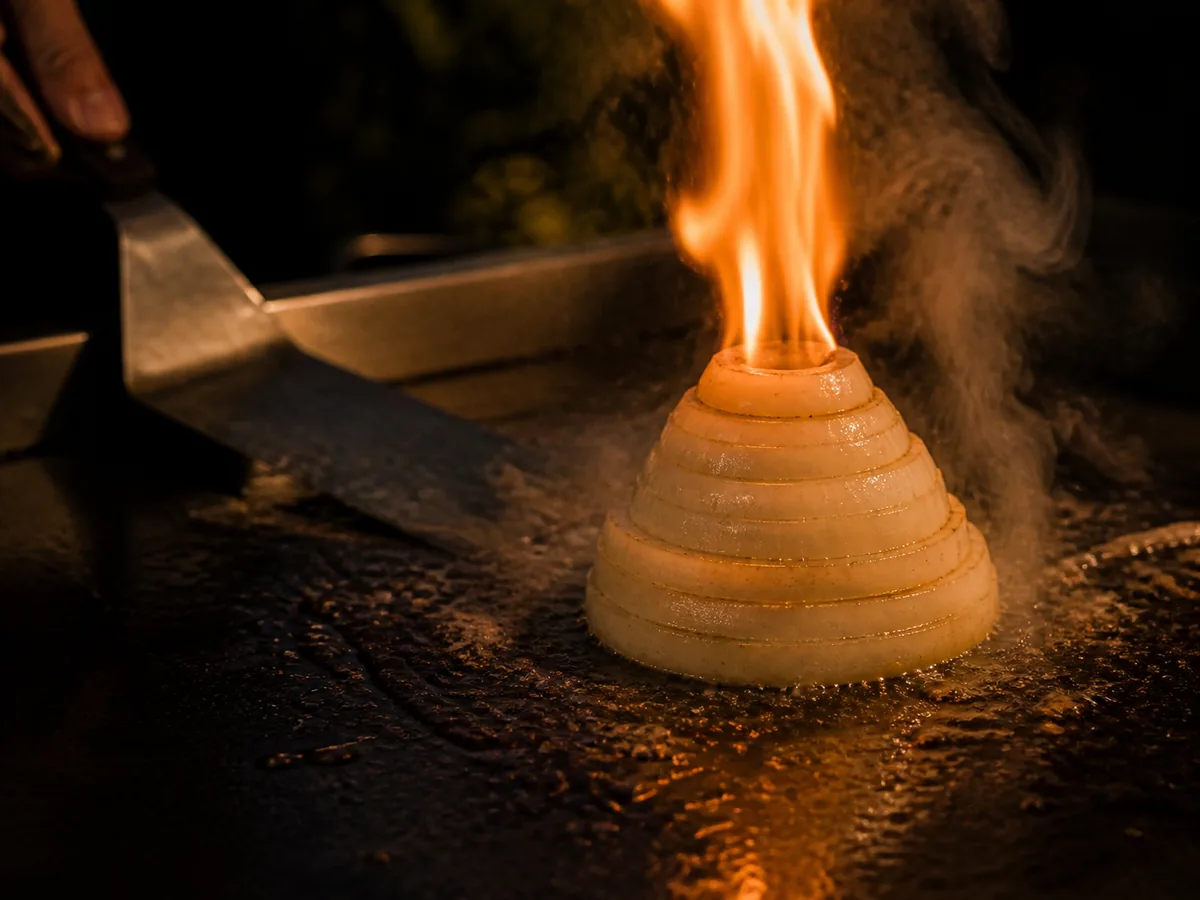 A stacked onion volcano throwing a jet of flame on the flat-top