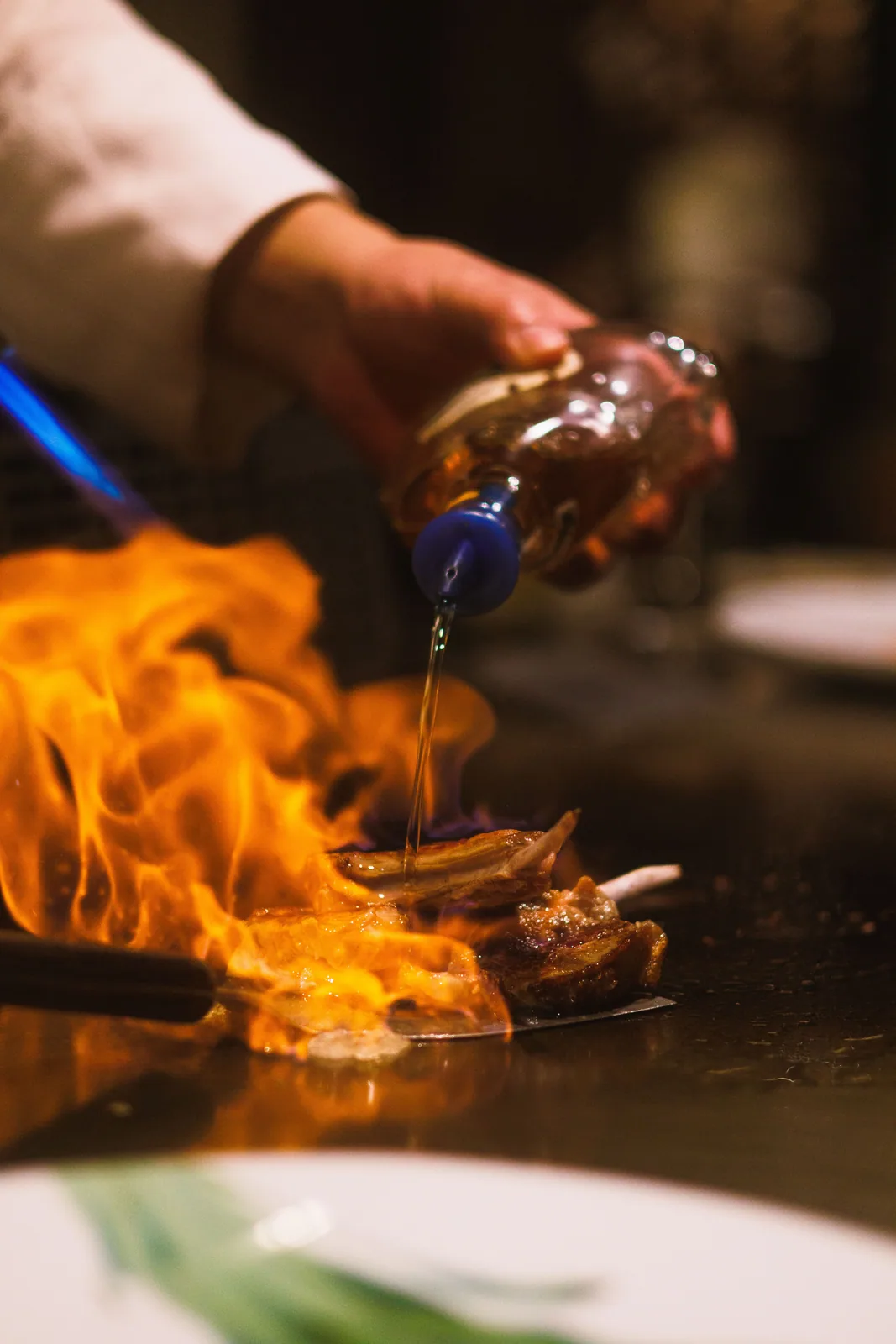 Meat searing on a flat-top as flames rise