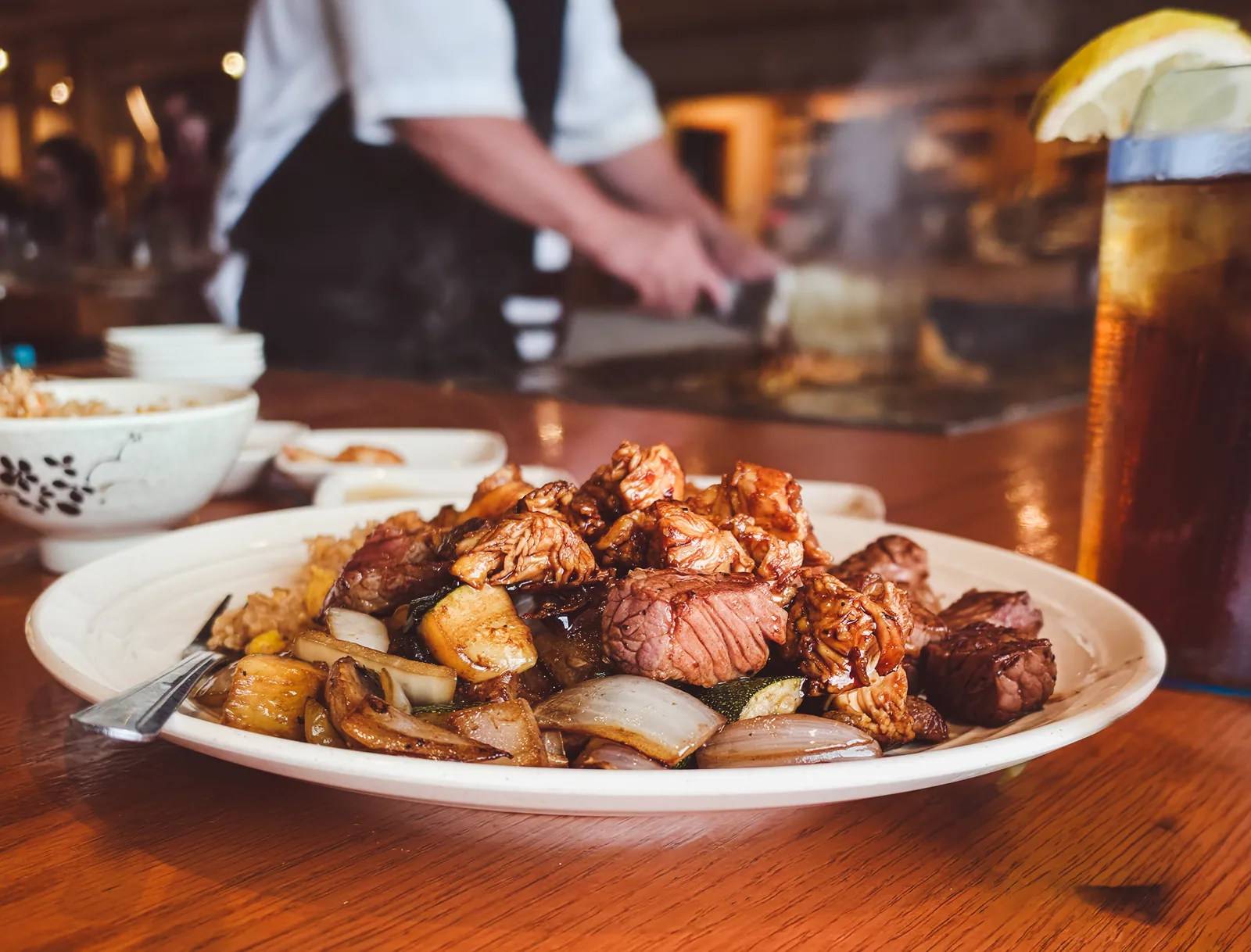 Chicken, steak and shrimp cooking together on a teppanyaki flat-top