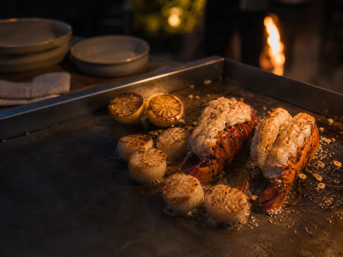 Lobster tails, scallops and charred lemon halves searing on the flat-top