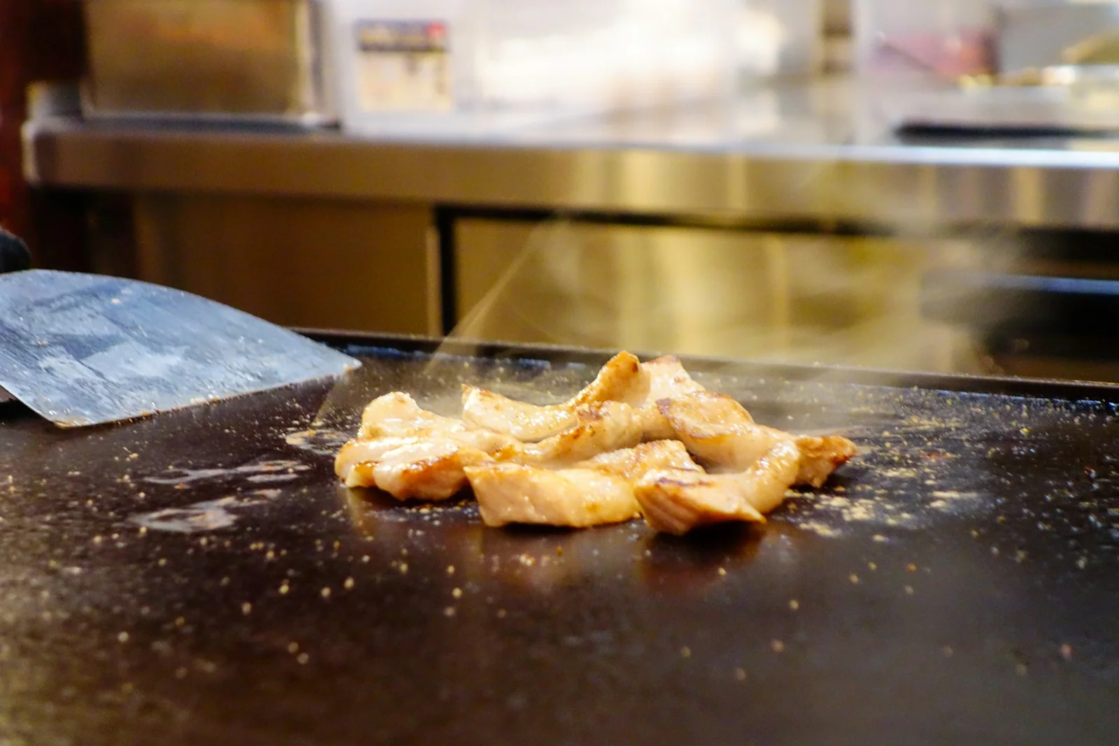 Chicken searing on a teppanyaki flat-top griddle