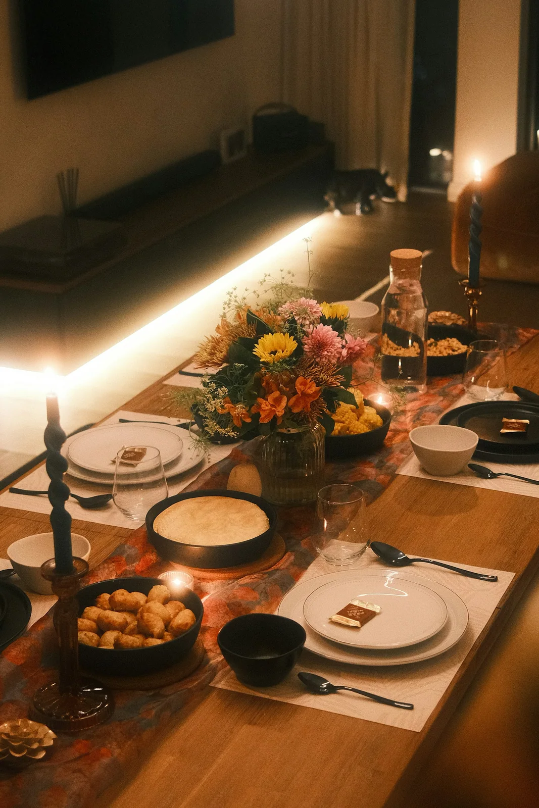A long table laid end to end with candles, flowers and place settings for a party