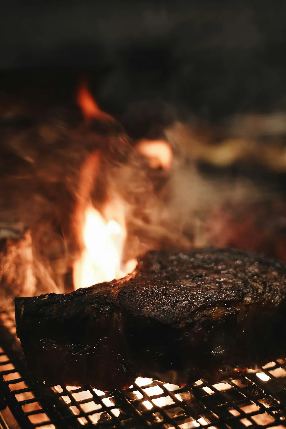 Meat searing directly over open flame on the grill