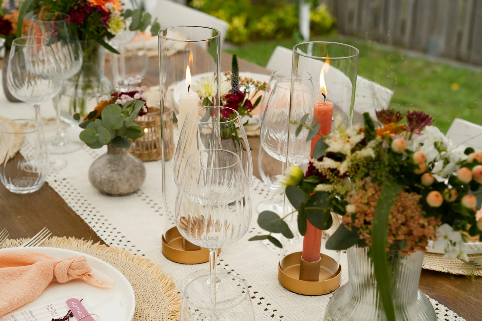 A close view of a laid table with glassware, candles and fresh flowers